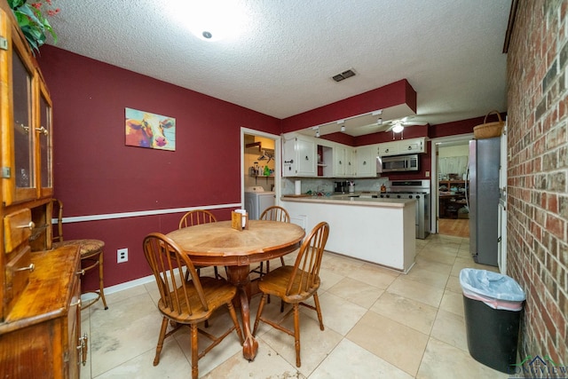 dining room with visible vents, a textured ceiling, independent washer and dryer, and a ceiling fan