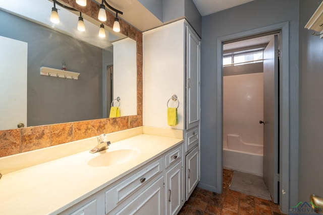 bathroom with a bath, vanity, and stone finish floor