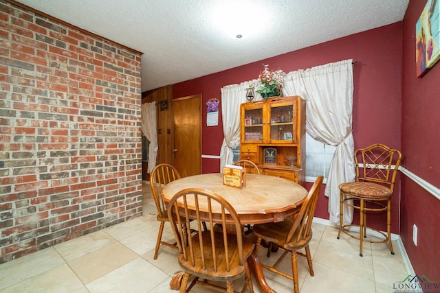 dining room featuring light tile patterned floors, brick wall, and a textured ceiling