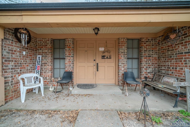 entrance to property featuring brick siding and a porch