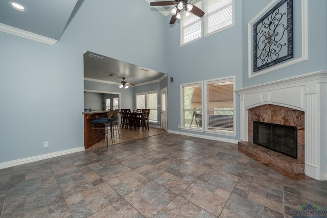 unfurnished living room with ceiling fan, ornamental molding, and a tile fireplace