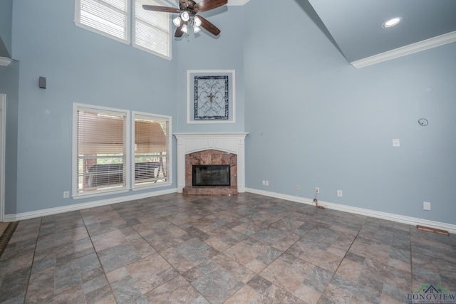 unfurnished living room featuring a tile fireplace, a high ceiling, ceiling fan, and ornamental molding