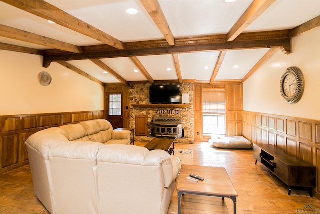 living room with a fireplace, vaulted ceiling with beams, light wood-type flooring, and wooden walls