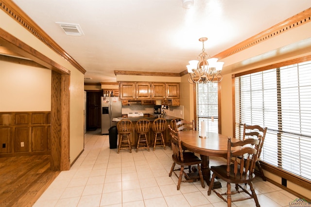 dining space featuring a notable chandelier, ornamental molding, and light tile patterned floors