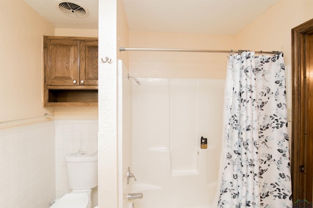 bathroom with tile walls and toilet