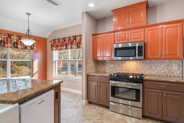 kitchen featuring lofted ceiling, appliances with stainless steel finishes, light stone countertops, and decorative backsplash