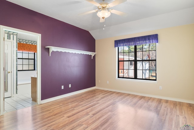 spare room with ceiling fan, lofted ceiling, and light wood-type flooring