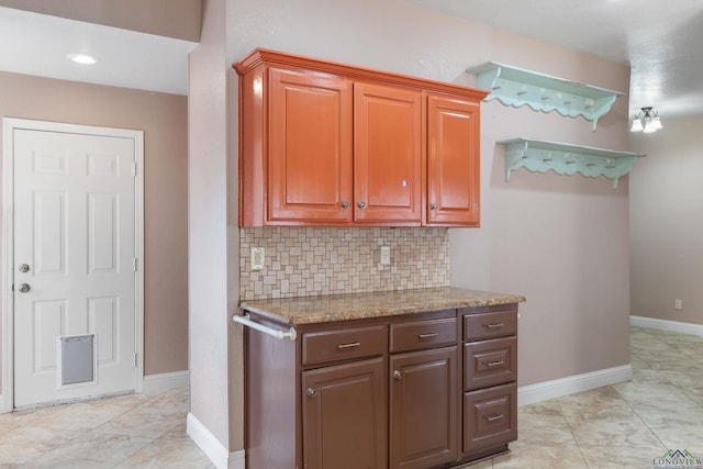 kitchen with light tile patterned flooring, light stone counters, and decorative backsplash