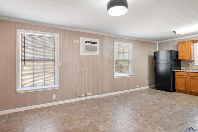 kitchen featuring light stone countertops, ornamental molding, an AC wall unit, and black refrigerator