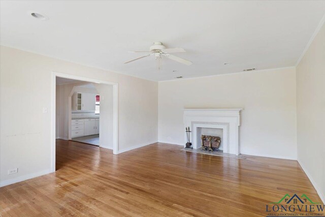 104 Mackinnon St, Mount Pleasant, TX 75455 - unfurnished living room with a ceiling fan, light wood-style floors, a fireplace with flush hearth, and baseboards