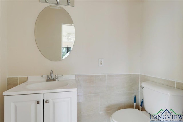 104 Mackinnon St, Mount Pleasant, TX 75455 - bathroom with toilet, vanity, tile walls, and wainscoting