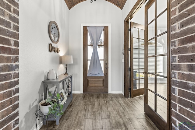 entryway featuring hardwood / wood-style floors, french doors, lofted ceiling, and brick ceiling