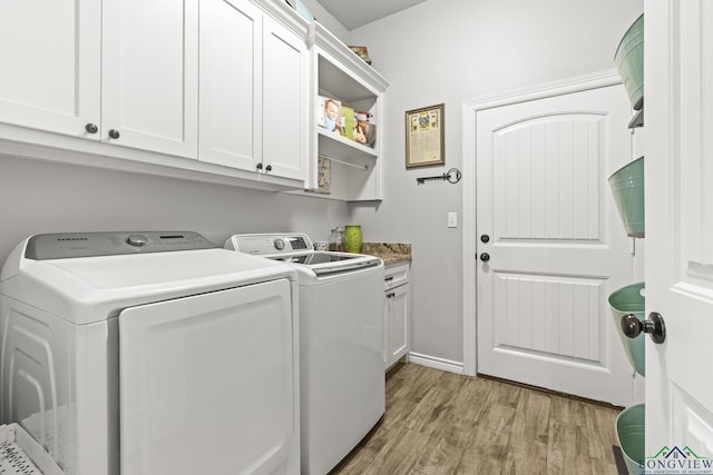 clothes washing area featuring cabinets, independent washer and dryer, and light wood-type flooring