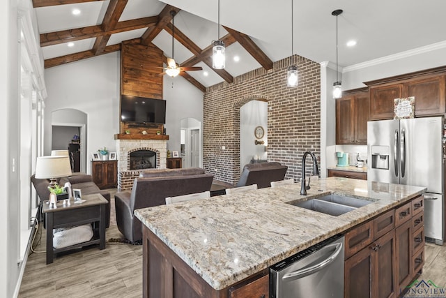 kitchen with beam ceiling, sink, stainless steel appliances, high vaulted ceiling, and a center island with sink