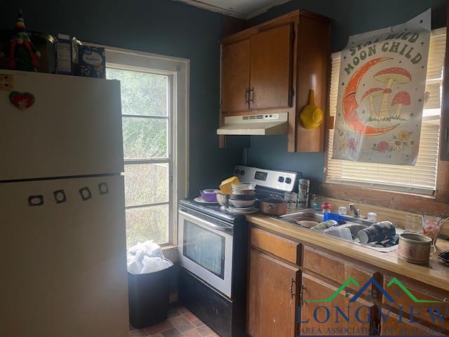 kitchen featuring stainless steel electric range oven, brown cabinets, freestanding refrigerator, light countertops, and under cabinet range hood