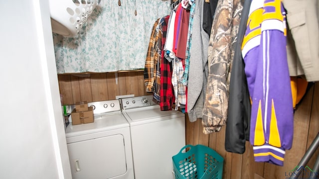 washroom featuring washing machine and clothes dryer and wooden walls