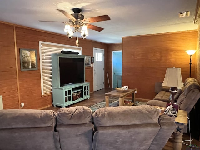 living room featuring wood-type flooring, ceiling fan, and wood walls