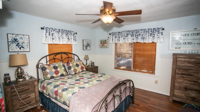 bedroom featuring a textured ceiling, ceiling fan, dark wood-type flooring, and wood walls