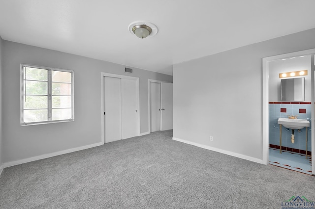202 W Rocky Creek Rd, Houston, TX 77076 - unfurnished bedroom with multiple closets, carpet floors, and baseboards