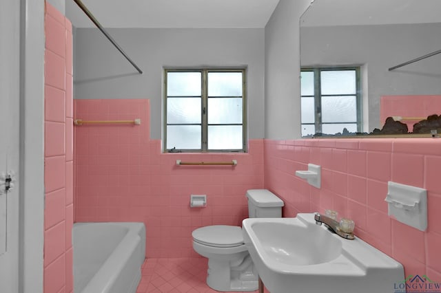 202 W Rocky Creek Rd, Houston, TX 77076 - bathroom featuring tile patterned flooring, tile walls, toilet, a sink, and a wainscoted wall