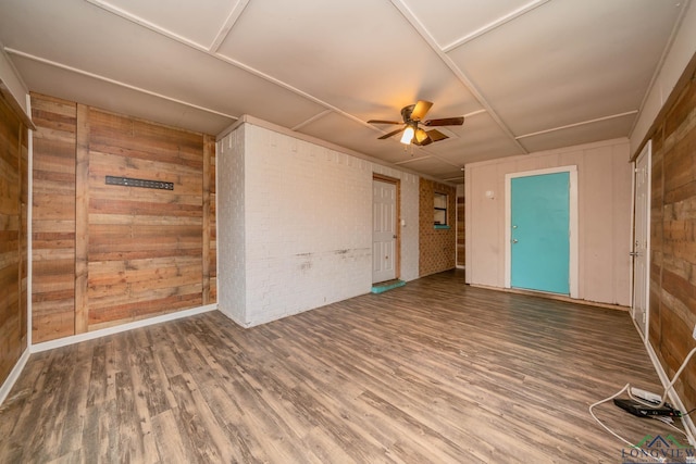 308 N Lee Dr, Gladewater, TX 75647 - spare room featuring ceiling fan, wooden walls, wood finished floors, and brick wall