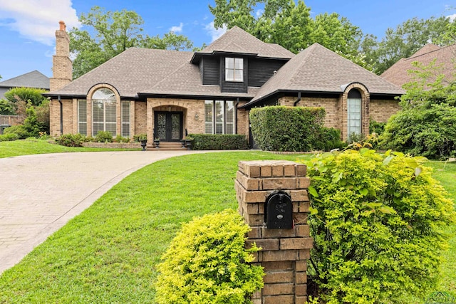 6307 Shady Oaks Dr, Tyler, TX 75703 - french provincial home featuring french doors, brick siding, a front lawn, a shingled roof, and a chimney