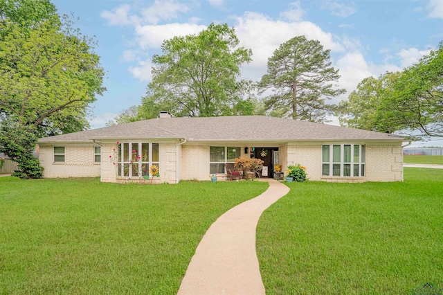 view of front facade featuring a front lawn, brick siding, and a chimney