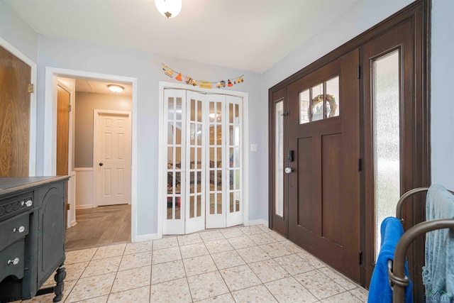 foyer entrance with baseboards and french doors