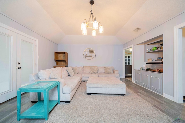 living room featuring wood finished floors, visible vents, built in shelves, and an inviting chandelier