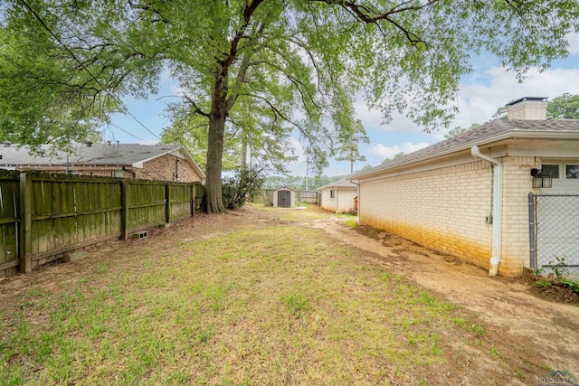view of yard with fence, a storage unit, and an outbuilding