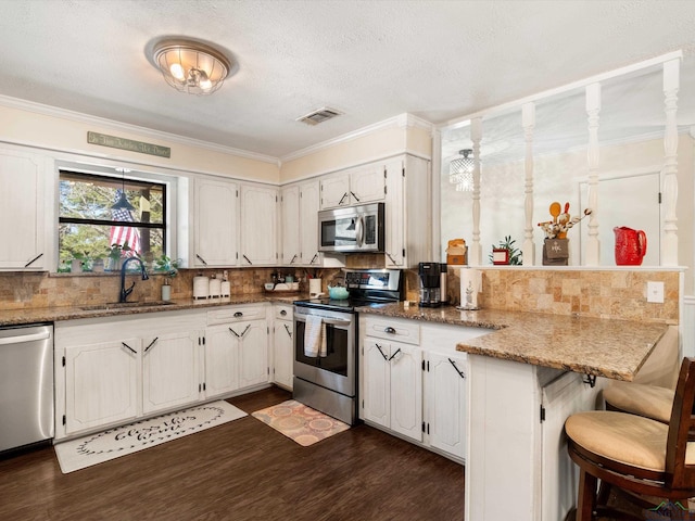 kitchen featuring tasteful backsplash, visible vents, appliances with stainless steel finishes, a peninsula, and a sink