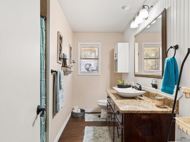 bathroom featuring vanity, toilet, wood finished floors, and baseboards