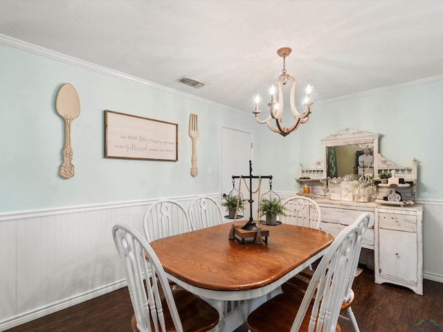 dining room with visible vents, ornamental molding, dark wood-style floors, wainscoting, and a chandelier