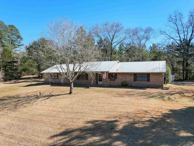 view of front of home with metal roof, brick siding, and a front lawn