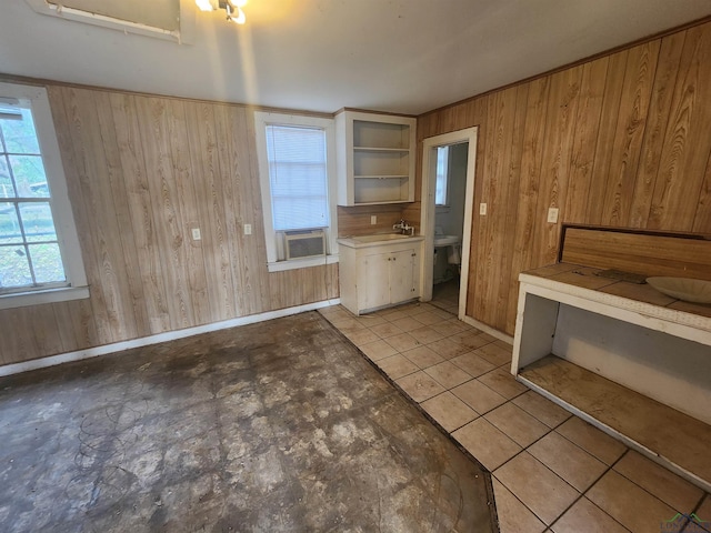 kitchen featuring sink, wooden walls, and light tile patterned flooring