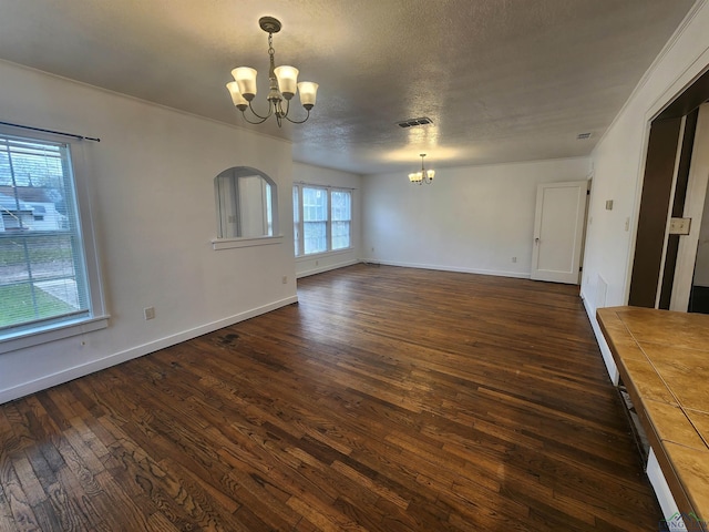 unfurnished living room with a textured ceiling, dark wood-type flooring, and a notable chandelier