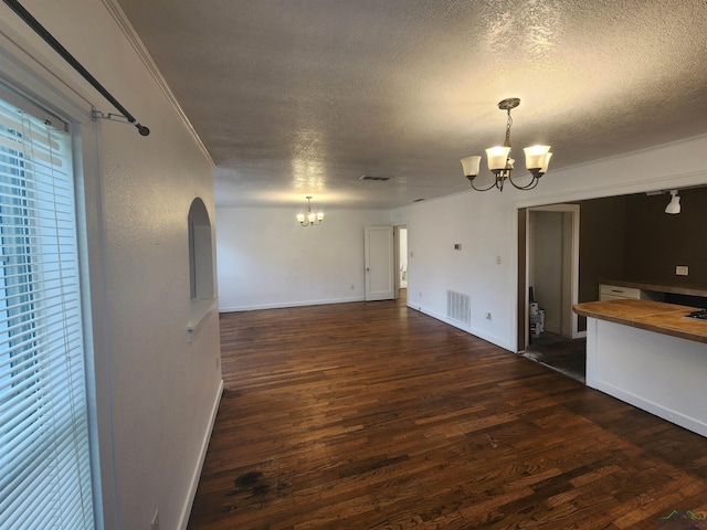 unfurnished living room with dark wood-type flooring, a textured ceiling, and an inviting chandelier