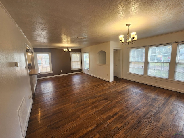 unfurnished living room with dark hardwood / wood-style flooring, a textured ceiling, and an inviting chandelier