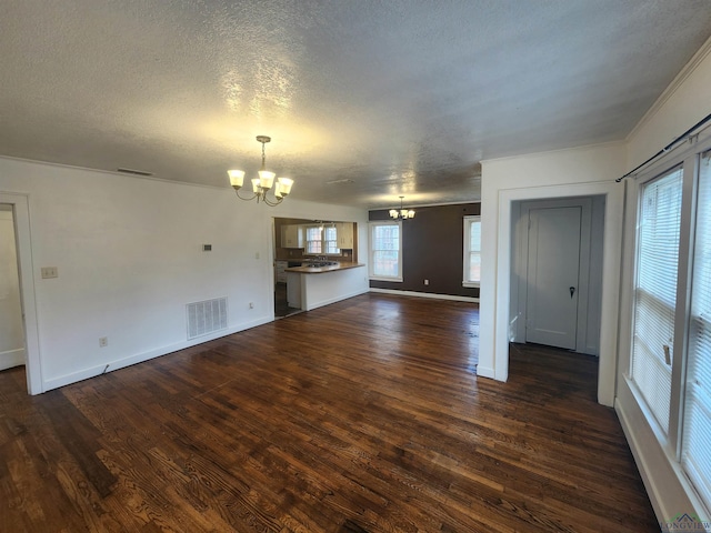 unfurnished living room featuring a textured ceiling, dark hardwood / wood-style flooring, and a notable chandelier