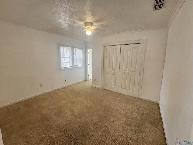 unfurnished bedroom featuring light carpet, crown molding, ceiling fan, a textured ceiling, and a closet