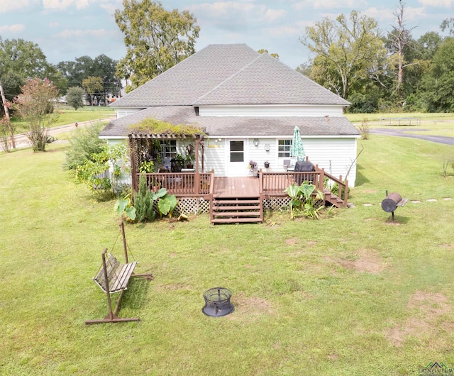 rear view of property featuring a fire pit, a lawn, and a wooden deck