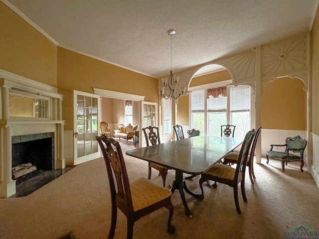 carpeted dining area with an inviting chandelier, lofted ceiling, a high end fireplace, and plenty of natural light