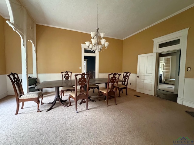 dining room with an inviting chandelier, vaulted ceiling, ornamental molding, and carpet