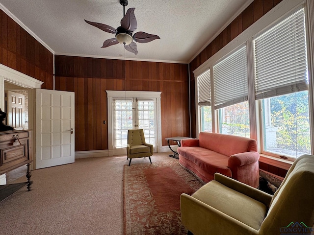 carpeted living room with crown molding, a textured ceiling, a healthy amount of sunlight, and wood walls