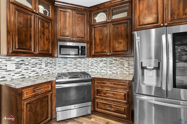 224 Stonegate Dr, Carthage, TX 75633 - kitchen with stainless steel appliances, tasteful backsplash, light stone counters, and wood finished floors