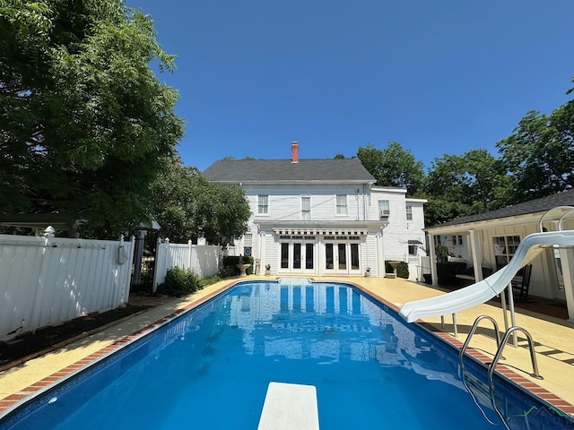 view of swimming pool with french doors, a diving board, a patio area, and a water slide