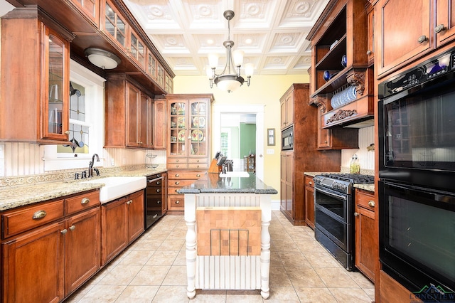 kitchen with light stone countertops, a center island, sink, light tile patterned floors, and black appliances