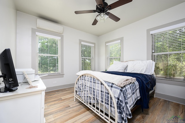 bedroom with an AC wall unit, ceiling fan, and hardwood / wood-style floors