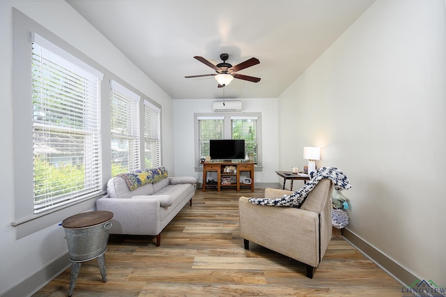 living room featuring a wealth of natural light, light wood-type flooring, a wall unit AC, and ceiling fan