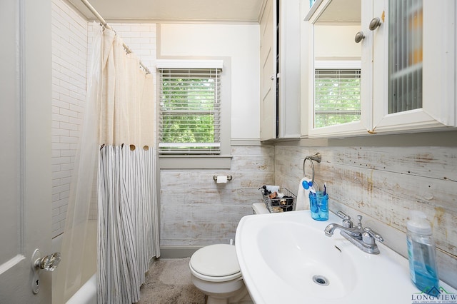 full bathroom with wood walls, toilet, sink, and shower / tub combo with curtain